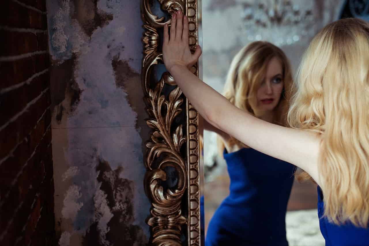 Image of a selfish self-obsessed woman staring at herself in the mirror