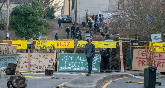 PORTLAND, OR - DECEMBER 09: An activists walks in front of barricades on December 9, 2020 in Portland, Oregon. Police and protesters clashed during an attempted eviction Tuesday, leading protesters to establish a barricade around the Red House. (Photo by Nathan Howard/Getty Images)