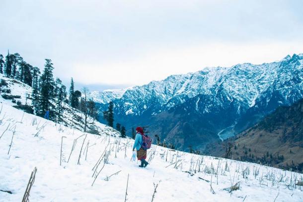 Woman walking through the Kashmir winter landscape. (gajendra / Adobe Stock)