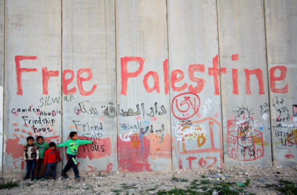 Palestinian children stand on the Jerusalem side of Israeli's separation barrier near the village of Abu Dis, April 03, 2014. (Photo: Saeed Qaq/APA Images)
