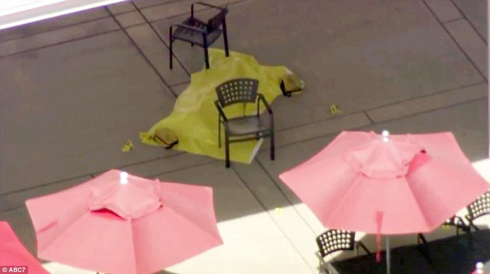 Authorities cover a body with a yellow tarp at YouTube¿s headquarters in the San Francisco Bay Area on Tuesday after a female shooter opened fire before she shot and killed herself