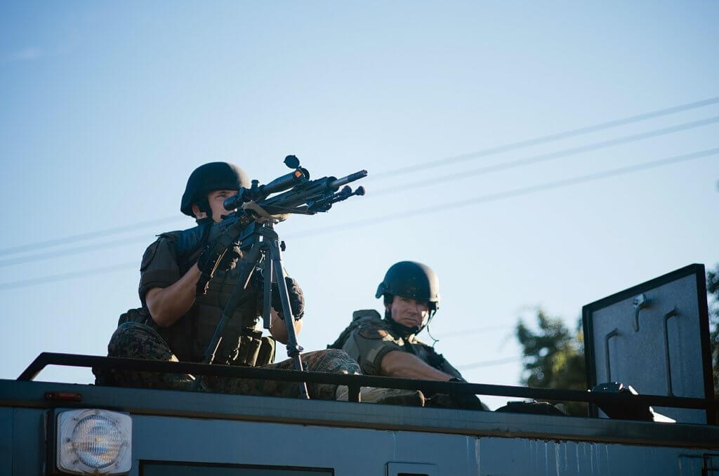 Sharpshooter, with weapon trained, atop a SWAT vehicle during the protests in Ferguson, MO following the police killing of Michael Brown, August 2014 (Photo: Jamelle Bouie/Wikimedia)