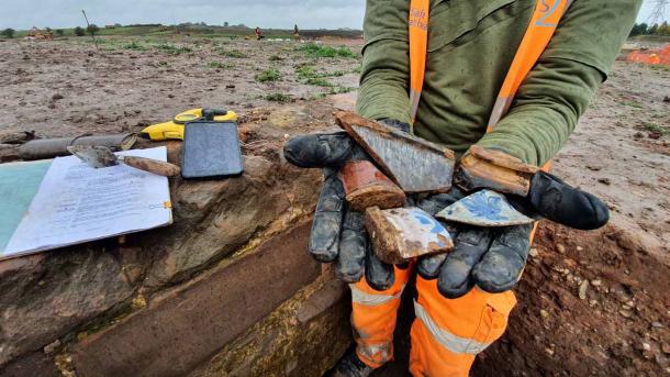 A Wessex archaeologist holds up post-medieval-era pottery found at the Coleshill Manor site. (HS2 Ltd.)