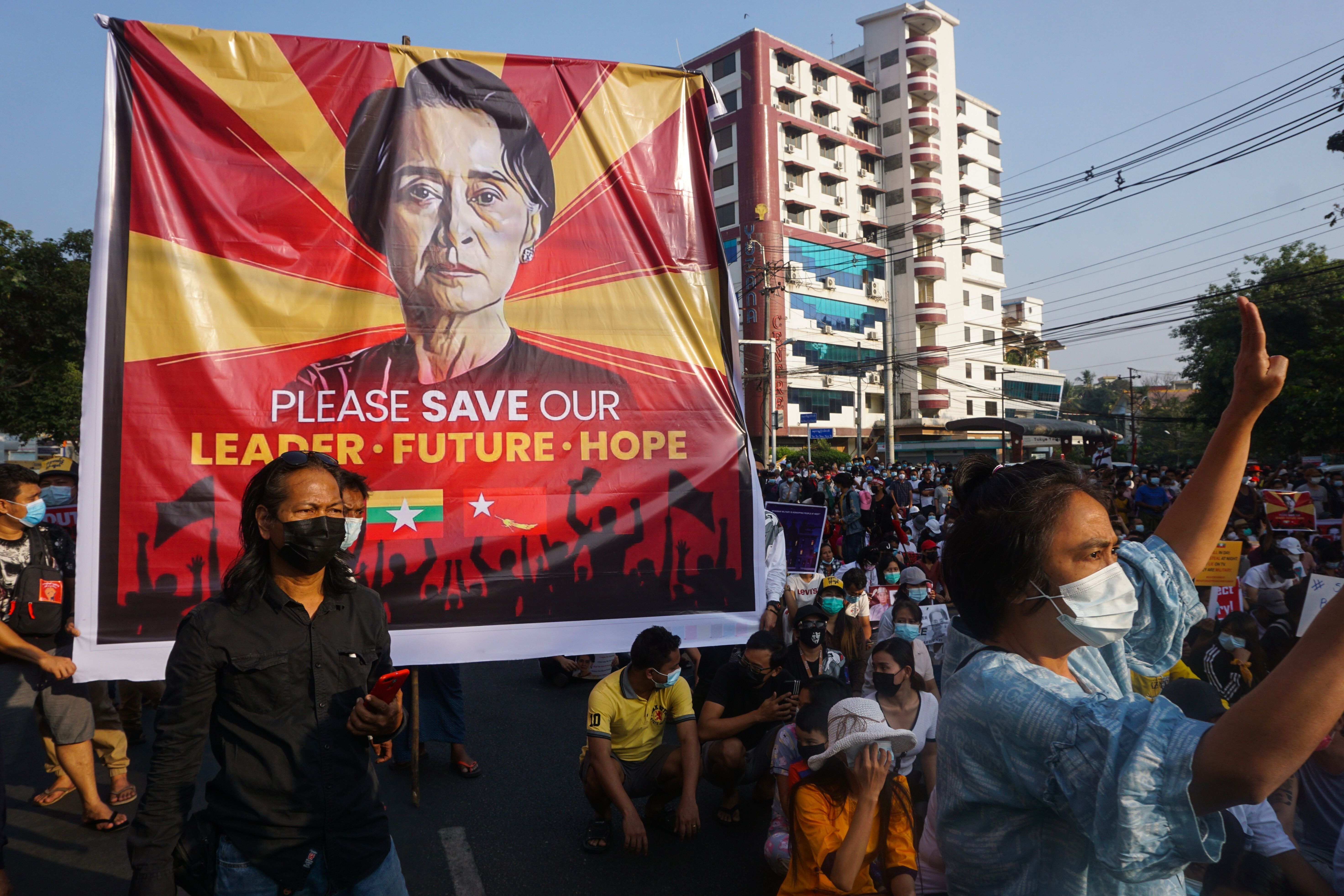 A banner featuring Aung San Suu Kyi is displayed as protesters take part in a demonstration against the military coup in fron