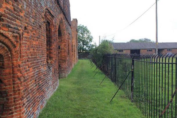Someries Castle is situated in the middle of Someries Farm, and is closely surrounded by stout metal railings, making wide shots of the ruins very difficult. This picture shows the nature of the gap around the sides, and the proximity of the farm buildings. (David P Howard / CC BY-SA 2.0)