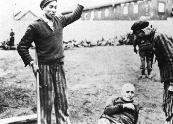 Newly liberated Dachau prisoners jeer a prostrate German prison guard