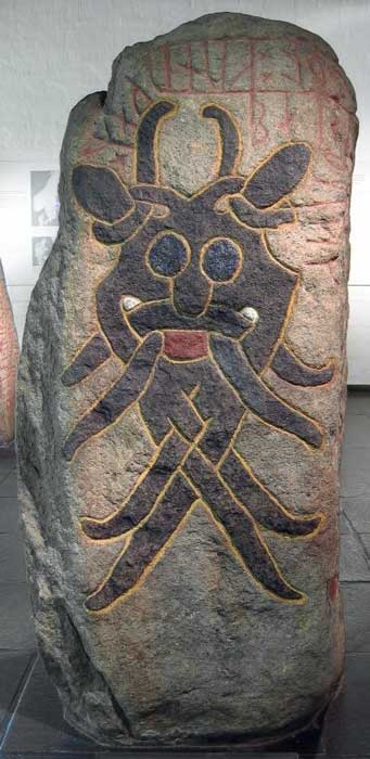 The Aarhus Mask Stone displays a very symmetrical mask with a happy or lunatic expression. The nose and eyes are very much like the Sjellebro Mask Stone. The runes say: "Gunnulfr and Eygautr/Auðgautr and Áslakr and Hrólfr raised this stone in memory of Fúl, their partner, who died when kings fought." (Gardar Rurak / CC BY-SA 4.0)