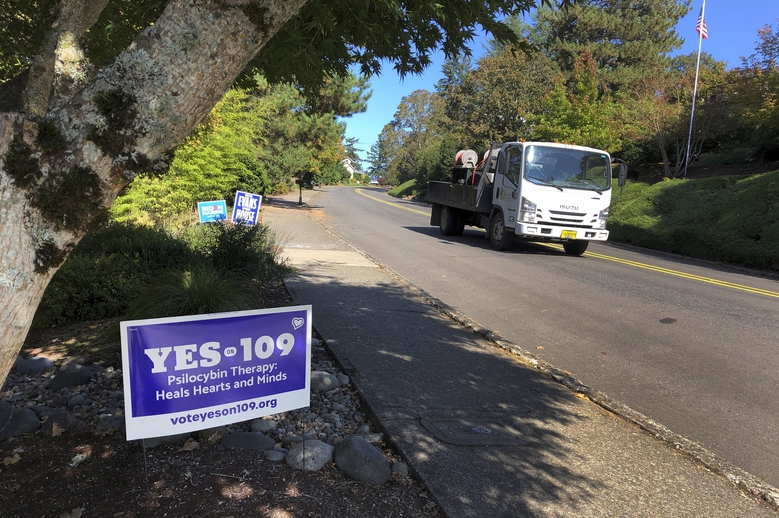 A truck drives past a sign supporting a ballot measure that would legalize controlled, therapeutic use of psilocybin mushrooms last month in Salem, Ore. (AP Photo/Andrew Selsky)