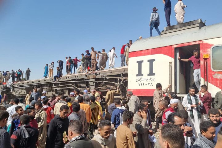 26 March 2021, Egypt, Tahta: People gather to inspect damaged train cars after two passenger trains collided near Tahta in So