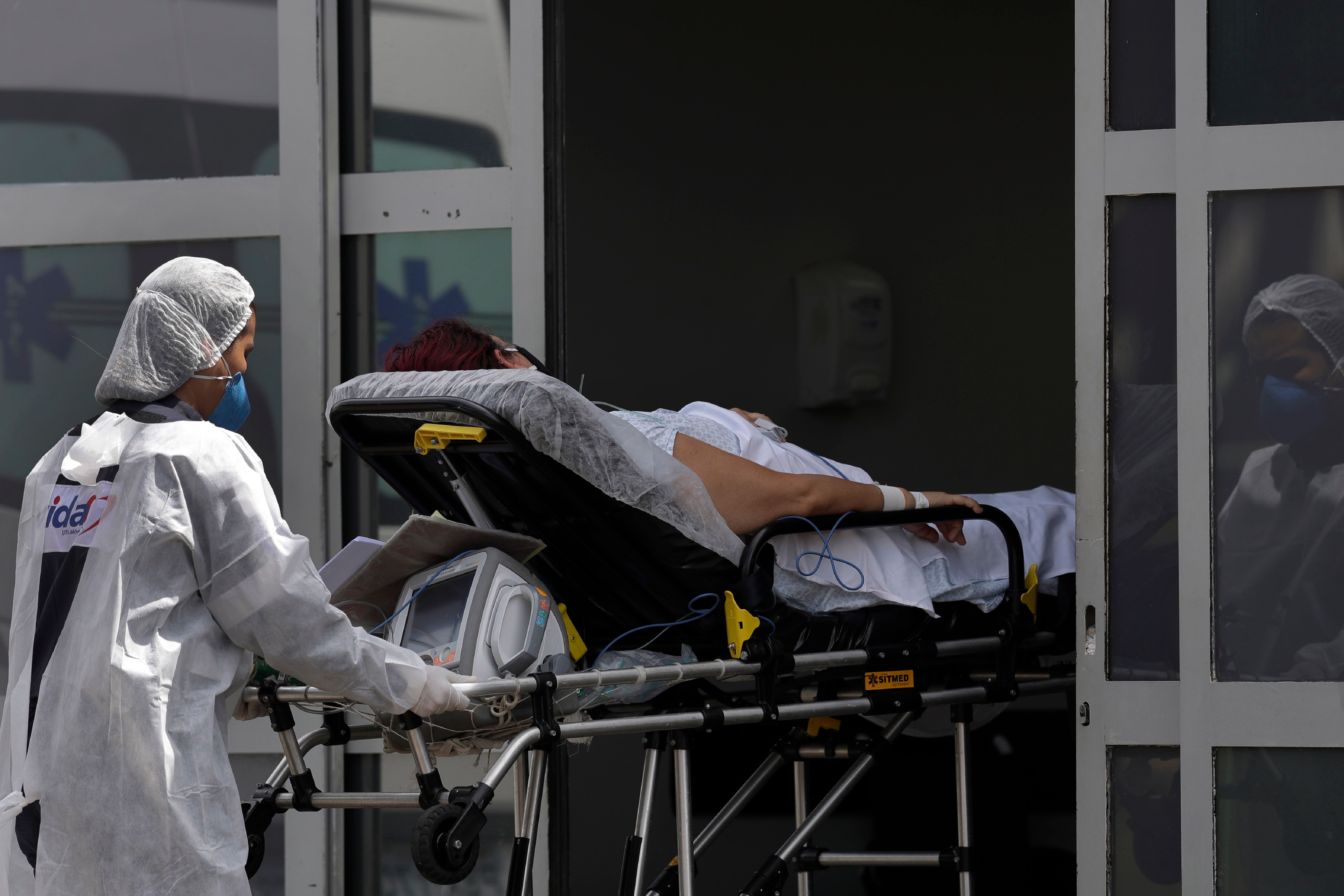 A healthcare worker pushes a patient suspected of having COVID-19 from an ambulance into the HRAN public hospital in Brasilia