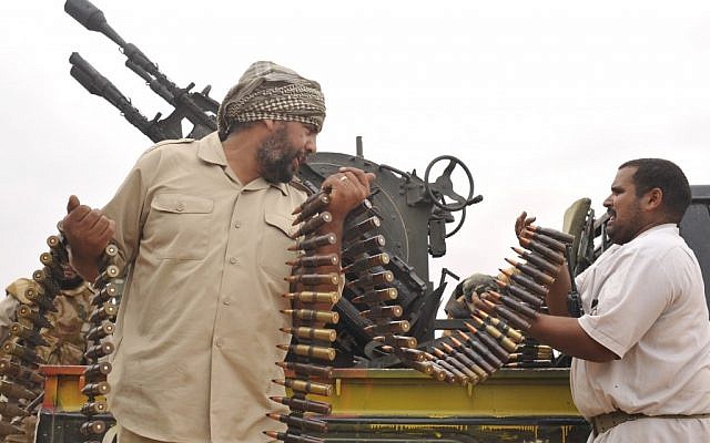 Libyan revolutionary fighters load their machine gun during an attack against pro-Gadhafi forces in 2011. (photo credit: AP/Bela Szandelszky)