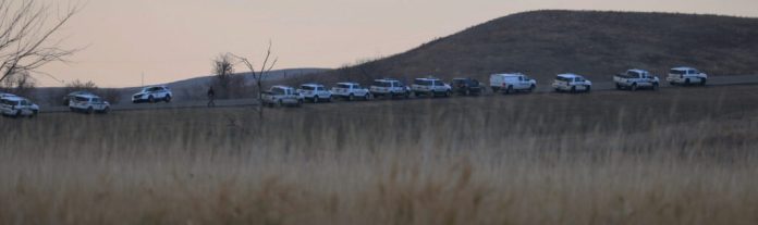 More than a dozen police vehicles line a North Dakota road at sunset