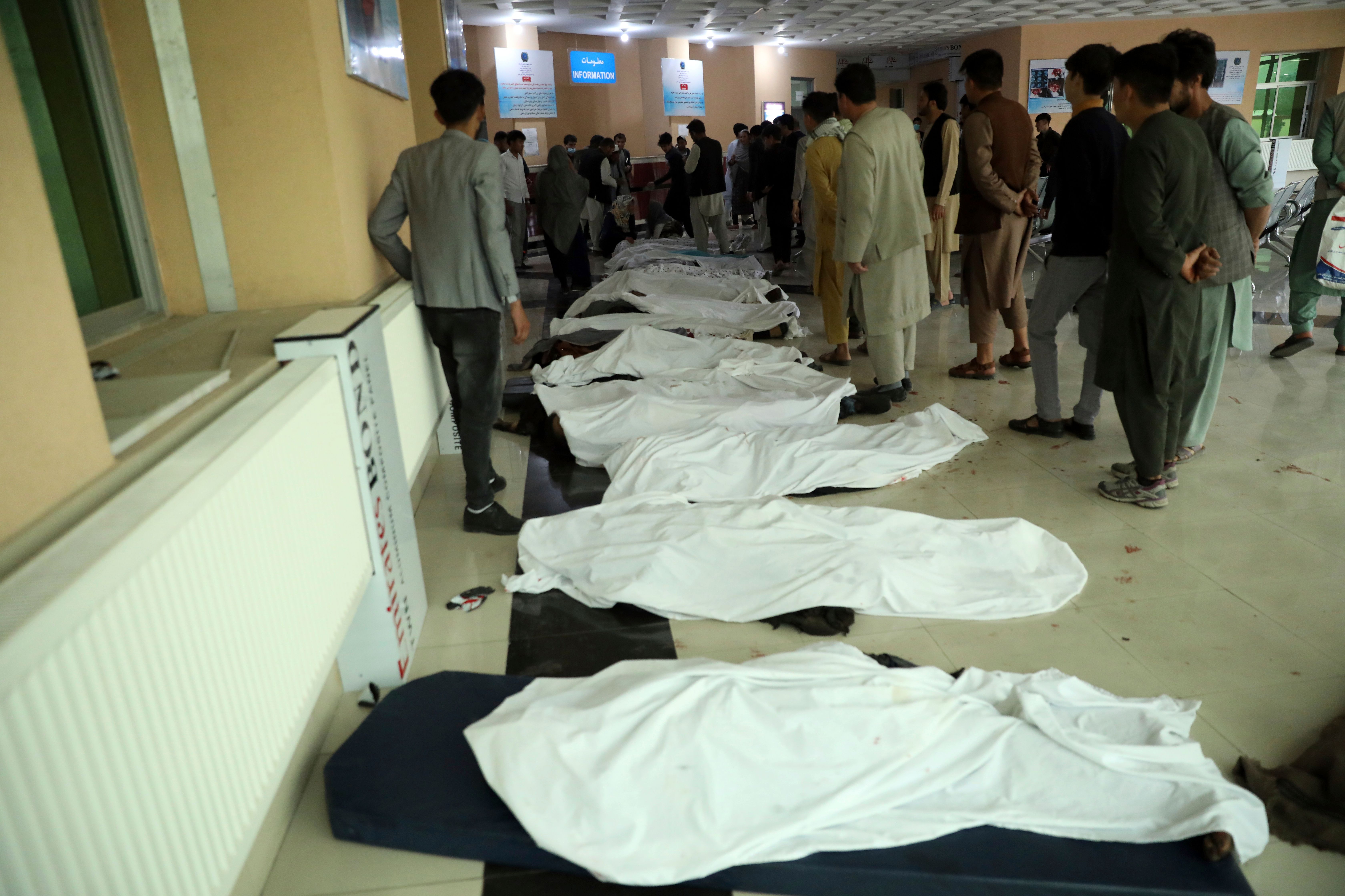 Afghan men try to identify the dead bodies at a hospital after a bomb explosion near a school west of Kabul, Afghanistan, Sat