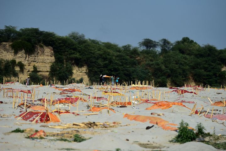 Relatives carry a dead body past shallow graves covered with saffron cloth&nbsp;on the banks of the Ganges River in Shringver