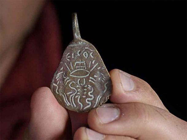 The flip side of the bronze Byzantine amulet shows an eye pierced by arrows and a pitchfork. (Dafna Gazit / Israel Antiquities Authority)