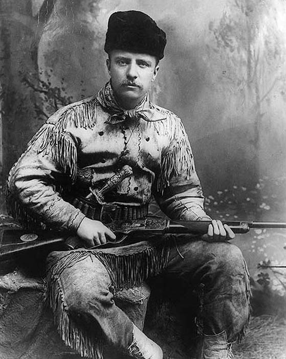 Theodore Roosevelt as the Badlands hunter. Theodore Roosevelt is in a hunting suit, and has a carved Tiffany hunting knife and rifle. Photographed by George Grantham Baine in 1885 in New York City. (Public Domain)