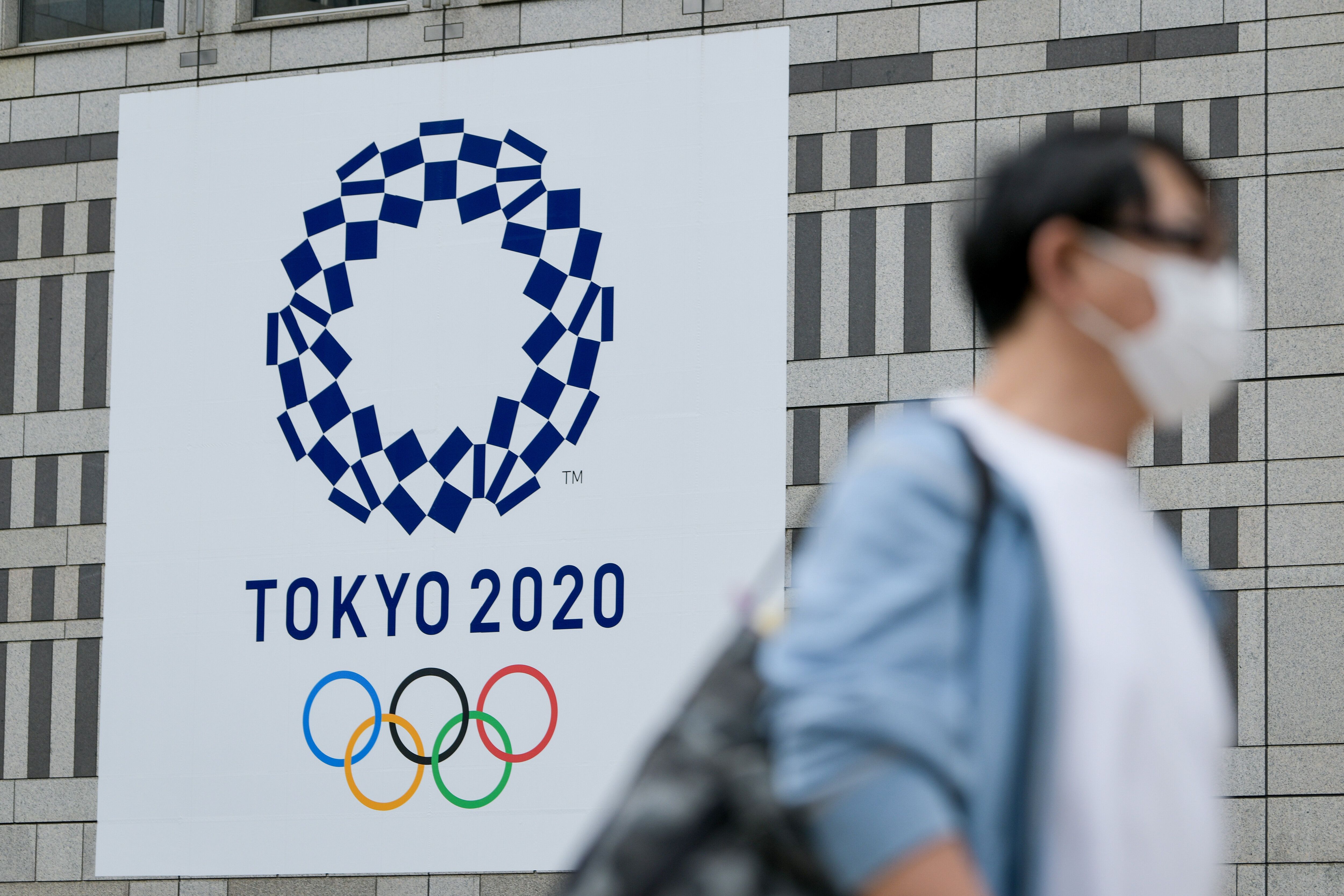 A man walks past a Tokyo 2020 banner on a building in Shinjuku area of Tokyo.