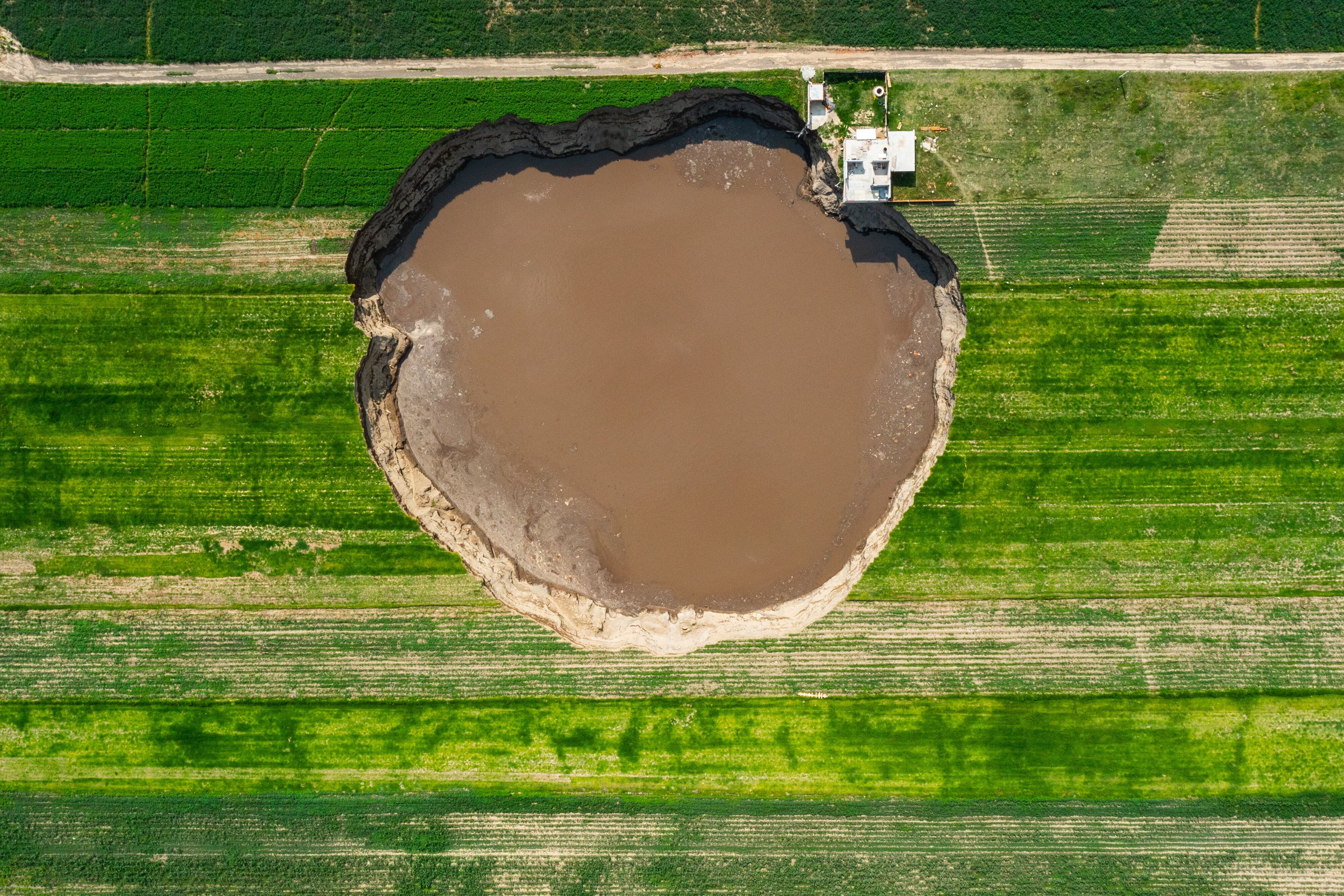 The large sinkhole that appeared in late May at a farm in central Mexico has grown larger than a football field, begun swallo