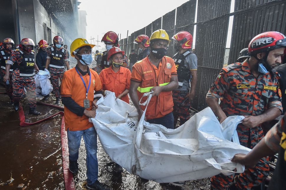 Rescue workers recover the bodies of the deceased who died in the blaze on Friday.