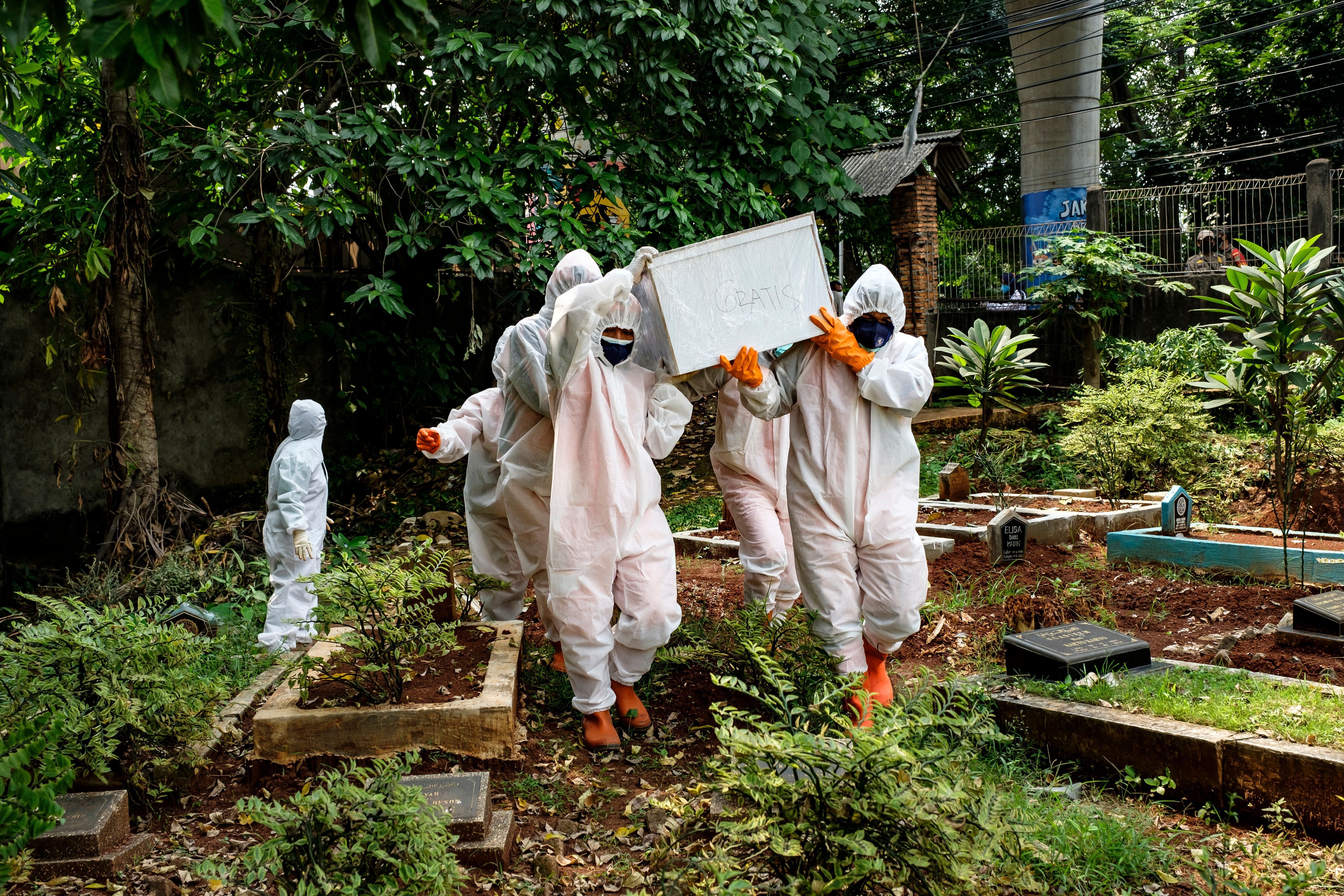 Health workers carry a casket containing the body of a suspected victim of COVID-19, who died at home in Jakarta, Indonesia.
