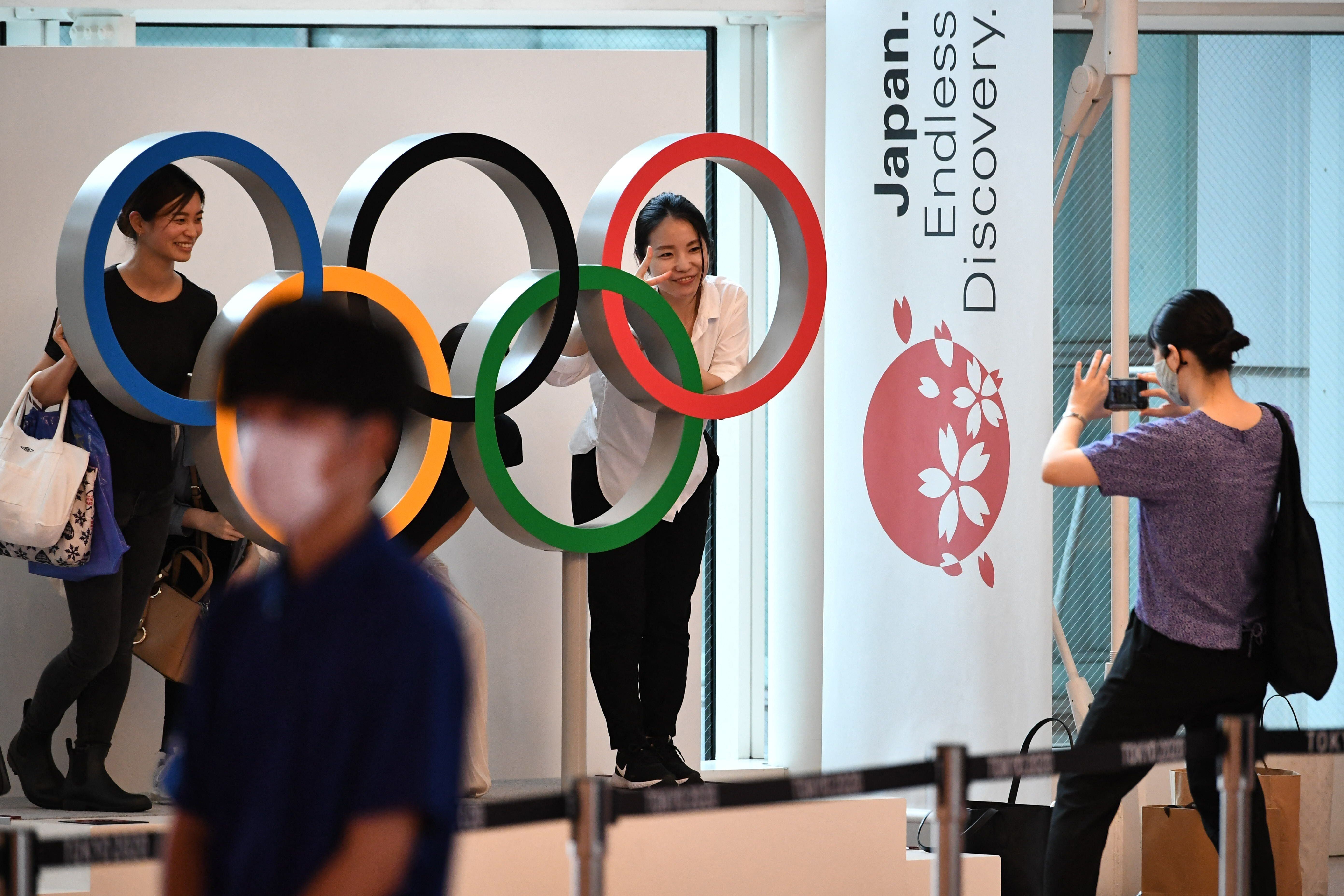 People take pictures with the Olympic rings displayed at the arrival lobby in the Tokyo International Airport in Tokyo on Thu