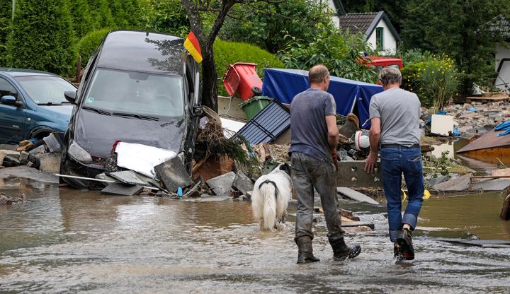 People clean up a street with damaged cars and houses in Hagen, Germany.