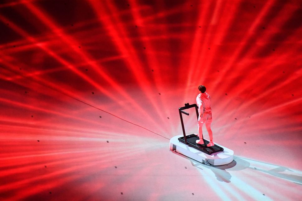 An overview shows a performer walking on a treadmill during the opening ceremony.