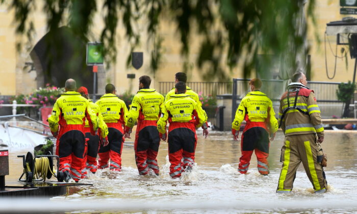 Lifeguards walk through a flooded street, following heavy rainfalls, in Valkenburg, Netherlands, July 15, 2021. (Piroschka Van De Wouw/Reuters)