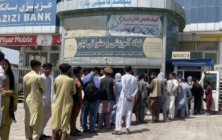 Afghan people line up outside AZIZI Bank to take out cash as the bank suffers amid money crises in Kabul, Afghanistan, on Sun