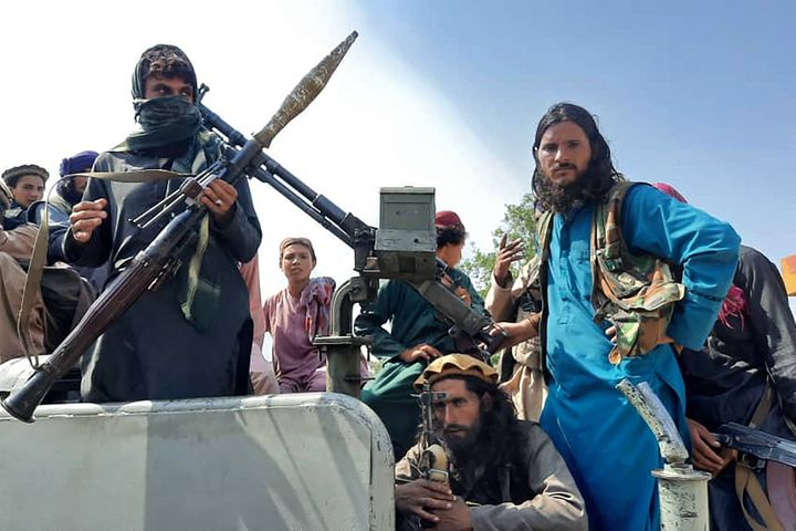 Taliban fighters sit over a vehicle on a street in Laghman province on Sunday.