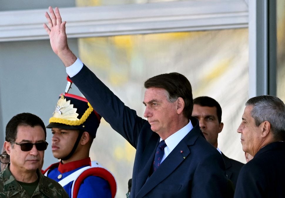 Flanked by a former general and the commander of the navy, far-right Brazil President Jair Bolsonaro watches a military parad