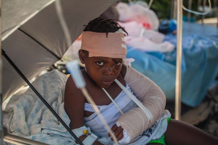 LES CAYES, HAITI - AUGUST 15: A boy is tended to outside Les Cayes General Hospital after a 7.2-magnitude earthquake struck 