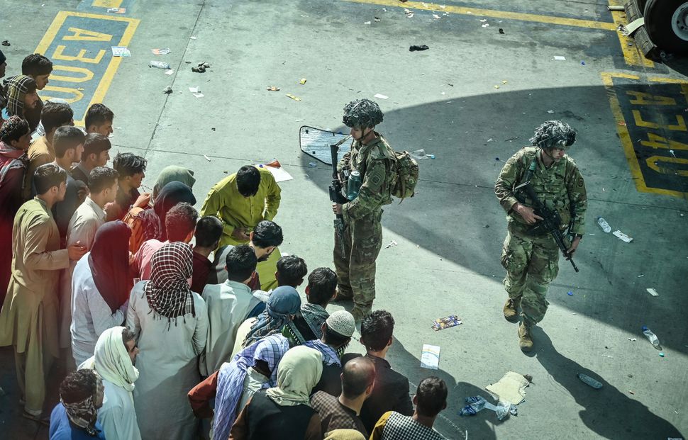 U.S. soldiers stand guard as Afghan people wait at the Kabul airport on Aug. 16, 2021.