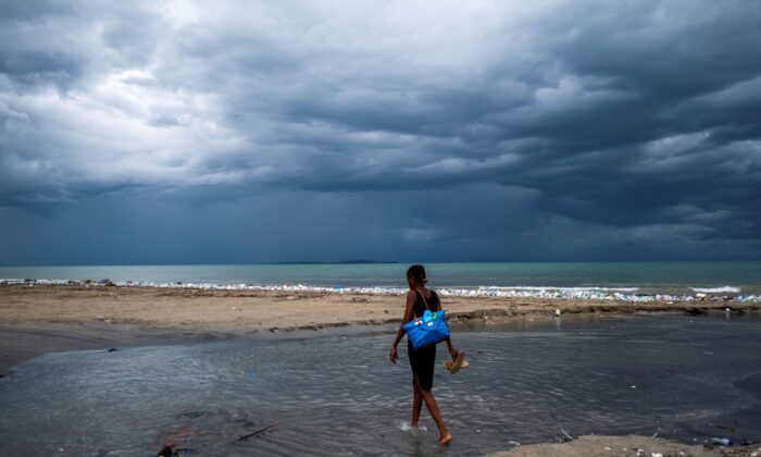 A woman wades through the water, as Tropical depression Grace approaches, after Saturday's 7.2 magnitude quake, in Les Cayes, Haiti, on Aug. 16, 2021. (Ricardo Arduengo/Reuters)