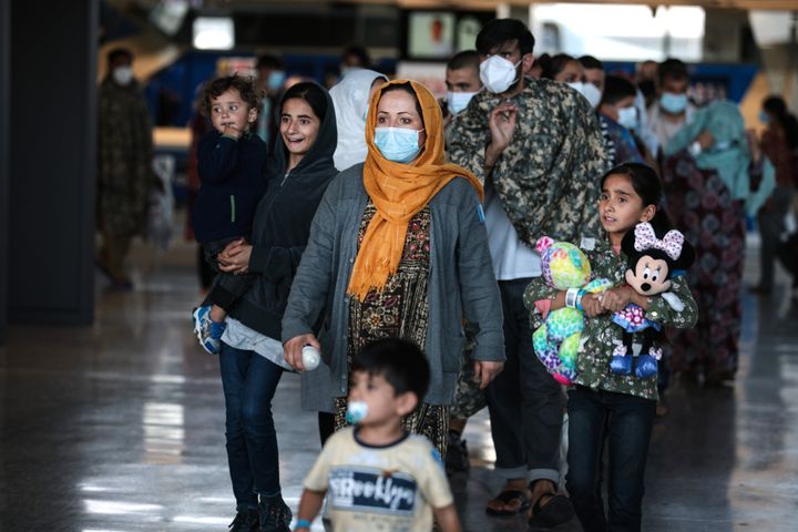 A family of people evacuated from Afghanistan are led through the arrival terminal at the Dulles International Airport to boa