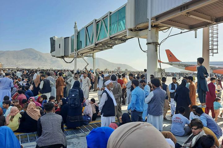 Afghans crowd the tarmac of the Kabul airport on Monday, attempting to flee the country as the Taliban takes control of Afgha
