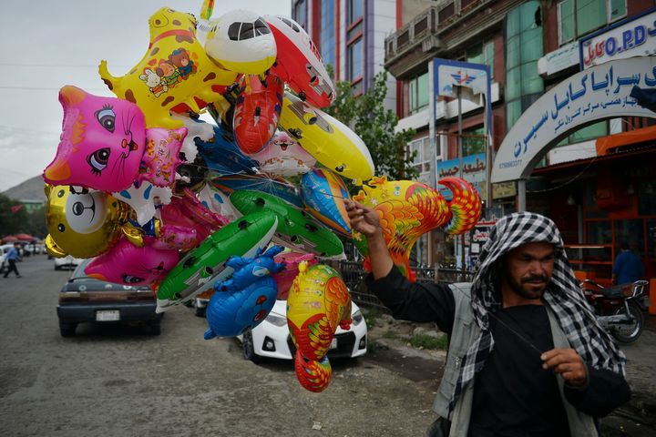 A balloon seller walks along a street in Kabul.