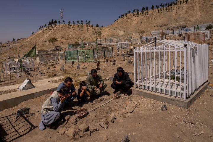 The Ahmadi family prays next to graves of family members killed by a U.S. drone strike in Kabul.