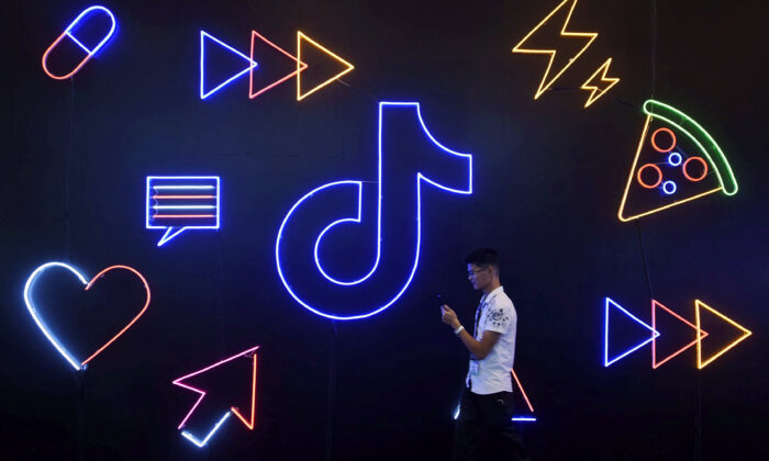 A man holding a phone walks past a sign of Chinese company ByteDance's app TikTok, known locally as Douyin, at the International Artificial Products Expo in Hangzhou, Zhejiang Province, China, on Oct. 18, 2019. (Stringer/Files/Reuters)
