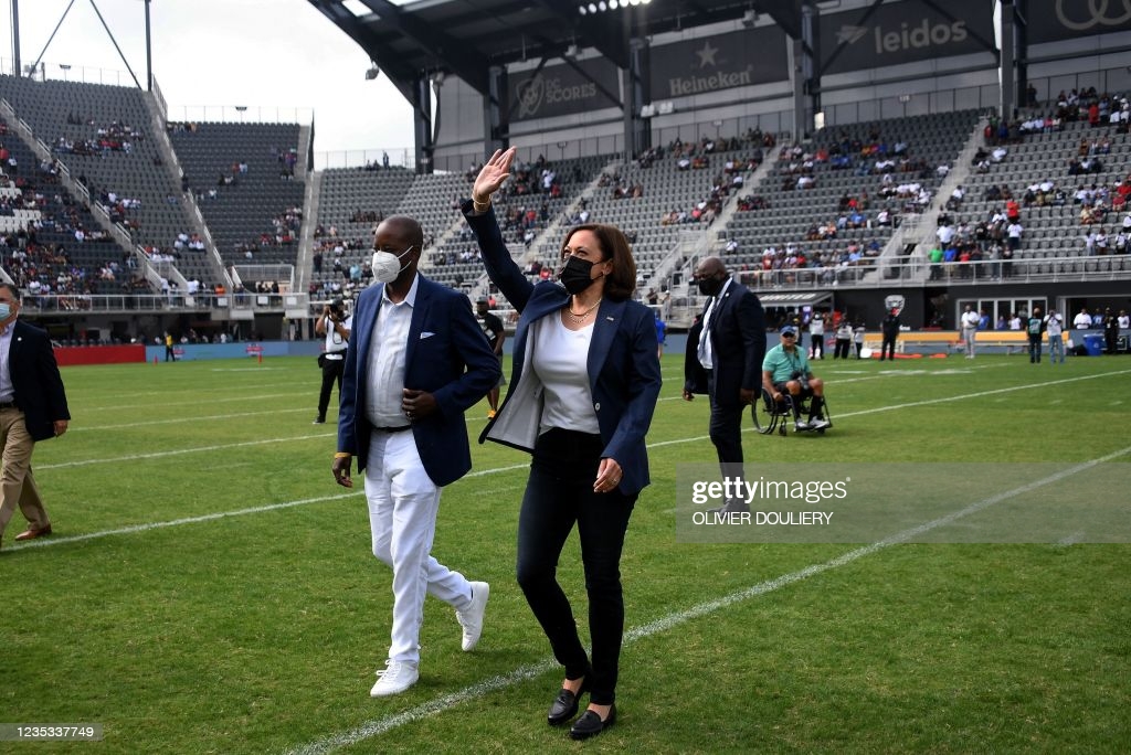 Vice President Kamala Harris, with Howard University President Wayne A. I. Frederick , waves as she leaves the field after tossing the coin for the...