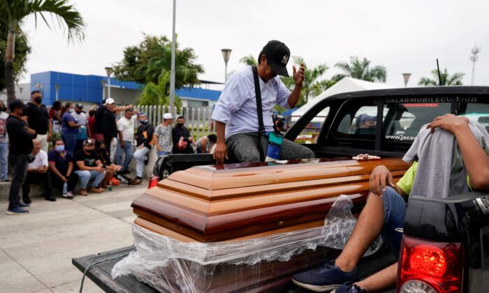 A casket is carried by a pickup truck as people gather outside the judicial police station after prisoners were killed and injured at the Penitenciaria del Litoral prison, in Guayaquil, Ecuador, on Nov. 14, 2021. (Santiago Arcos/Reuters)