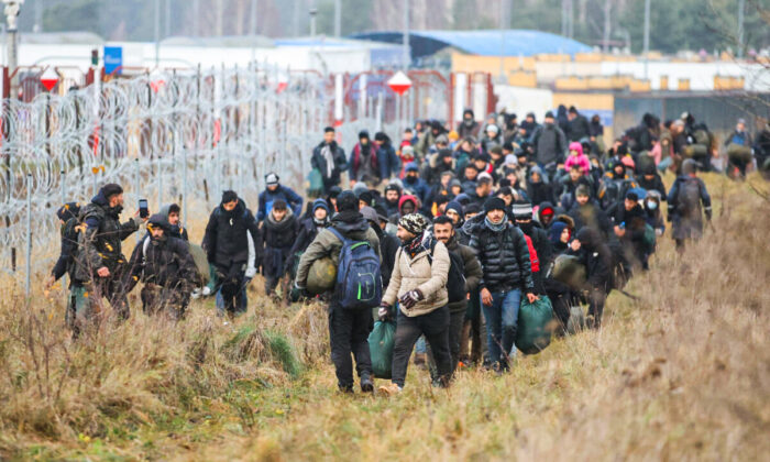 A group of migrants moves along the Belarusian-Polish border towards a camp to join those gathered at the spot and aiming to enter EU member Poland, in the Grodno region on Nov. 12, 2021. (Leonid Shcheglov/Belta/AFP via Getty Images)