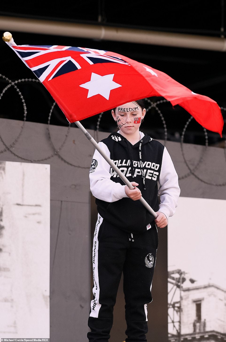 A child is seen holding a flag at the Melbourne CBD Freedom Rally on Saturday