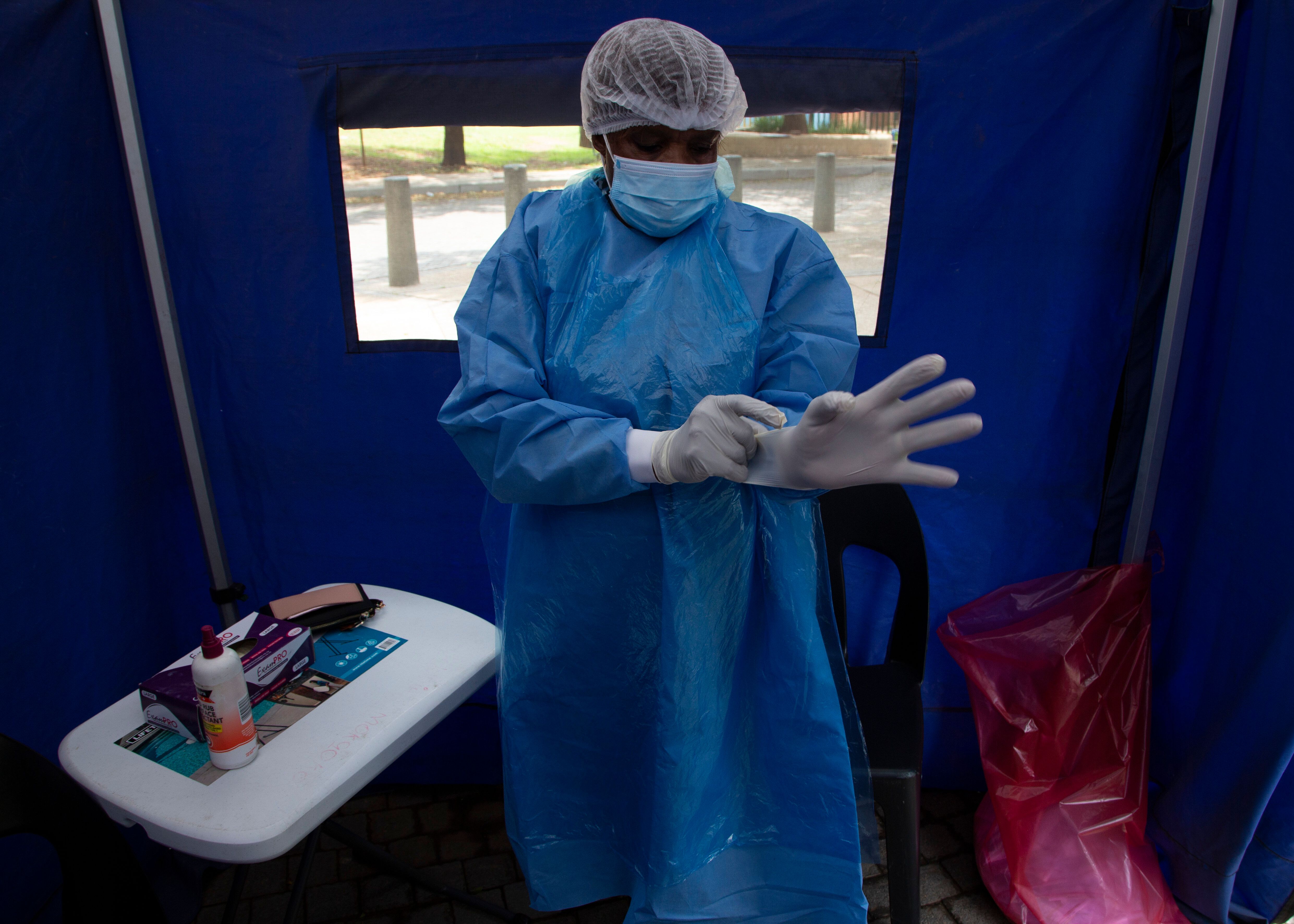 A healthcare worker prepares to test a person for COVID-19 at a facility in Soweto, South Africa, Wednesday Dec. 2, 2021. South Africa has accelerated its vaccination campaign by giving jabs at pop-up sites in shopping centers and transport hubs to combat the rapidly rising new cases of COVID-19.