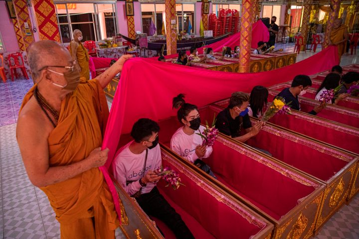 Thai monks cover devotees with a pink sheet during a resurrection ceremony at Wat Takien on Dec. 31, 2021, in Bangkok, Thailand. 