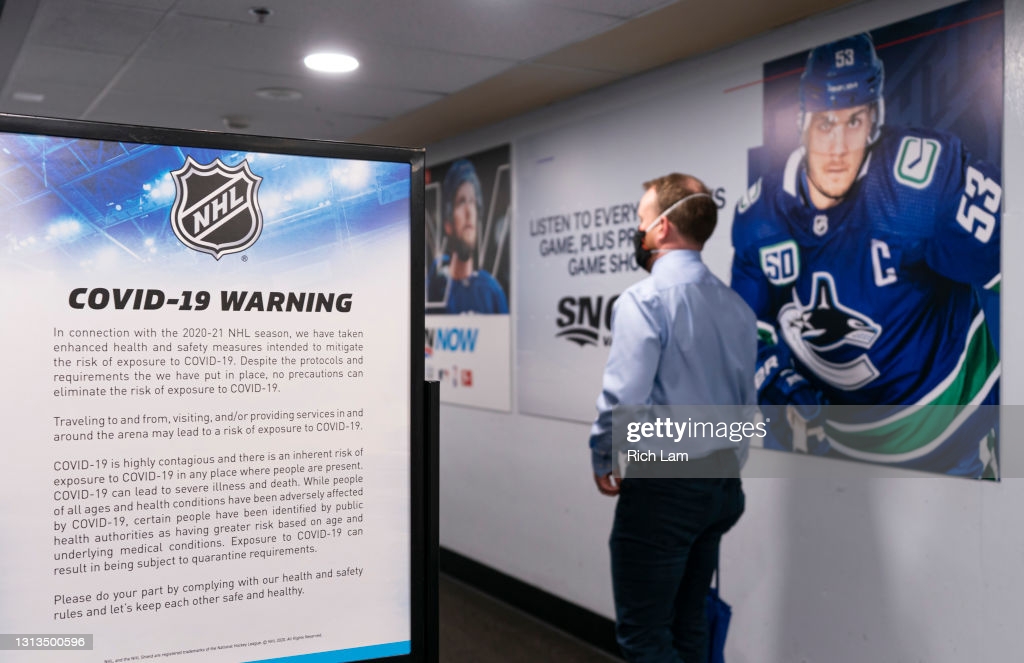 Man walks past a COVID-19 warning sign after entering Rogers Arena prior to NHL hockey action between the Vancouver Canucks and the Toronto Maple...