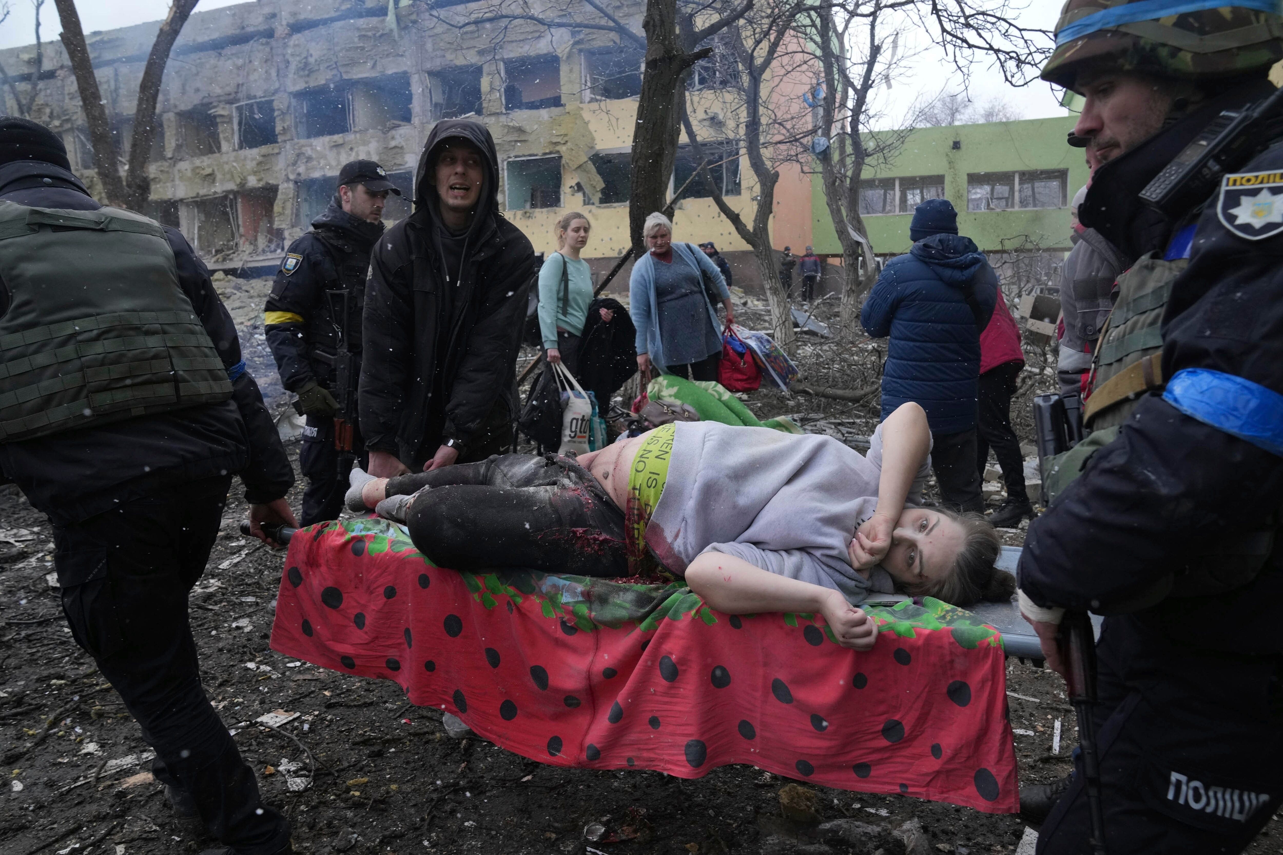 Ukrainian emergency employees and volunteers carry an injured pregnant woman from the damaged by shelling maternity hospital in Mariupol, Ukraine, Wednesday, March 9, 2022. A Russian attack has severely damaged a maternity hospital in the besieged port city of Mariupol, Ukrainian officials say.