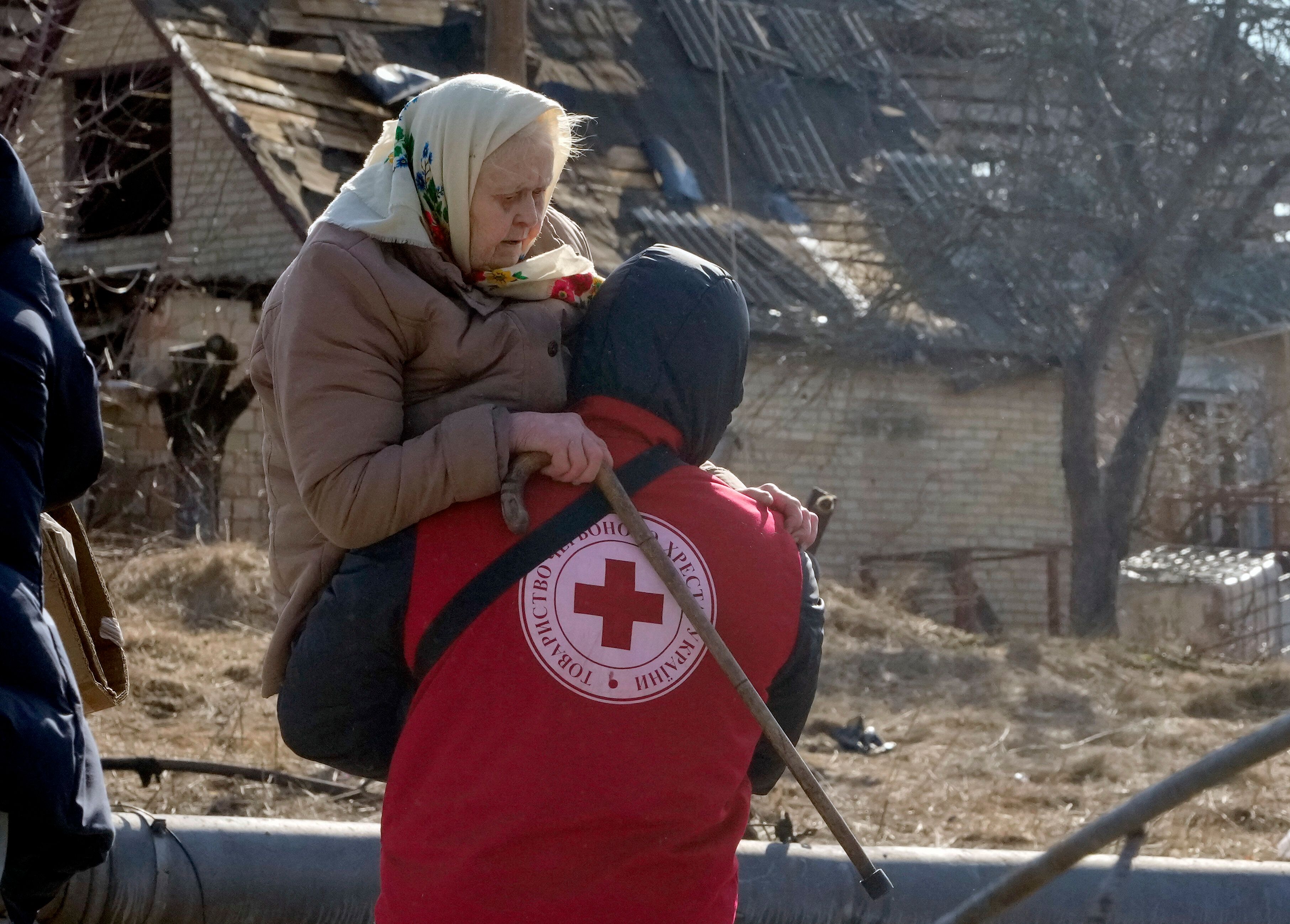 A Red Cross worker carries a woman during an evacuation in Irpin.
