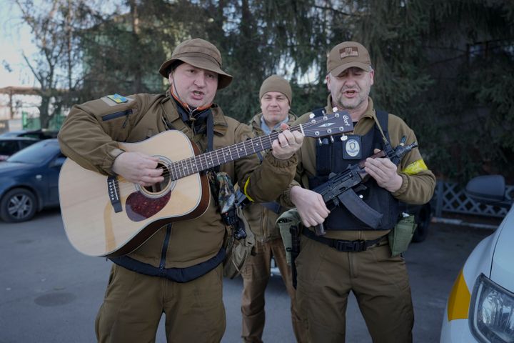 Members of the Ukrainian civil defense, one mimicking a guitar with his assault rifle, play a song while waiting to escort a fuel transport in Kyiv, Ukraine, Monday, Feb. 28, 2022. Explosions and gunfire that have disrupted life since the invasion began last week appeared to subside around Kyiv overnight, as Ukrainian and Russian delegations met Monday on Ukraine's border with Belarus. 