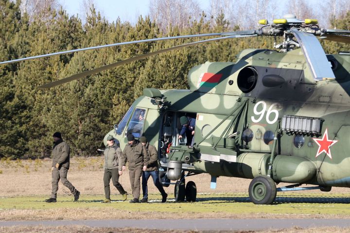 The Ukrainian delegation leaves a Belarusian military helicopter upon their landing in Gomel region, Belarus, Monday, Feb. 28, 2022. The Russian and Ukrainian delegations met for their first talks Monday. The meeting took place in Gomel region on the banks of the Pripyat River. (Sergei Kholodilin/BelTA Pool Photo via AP)